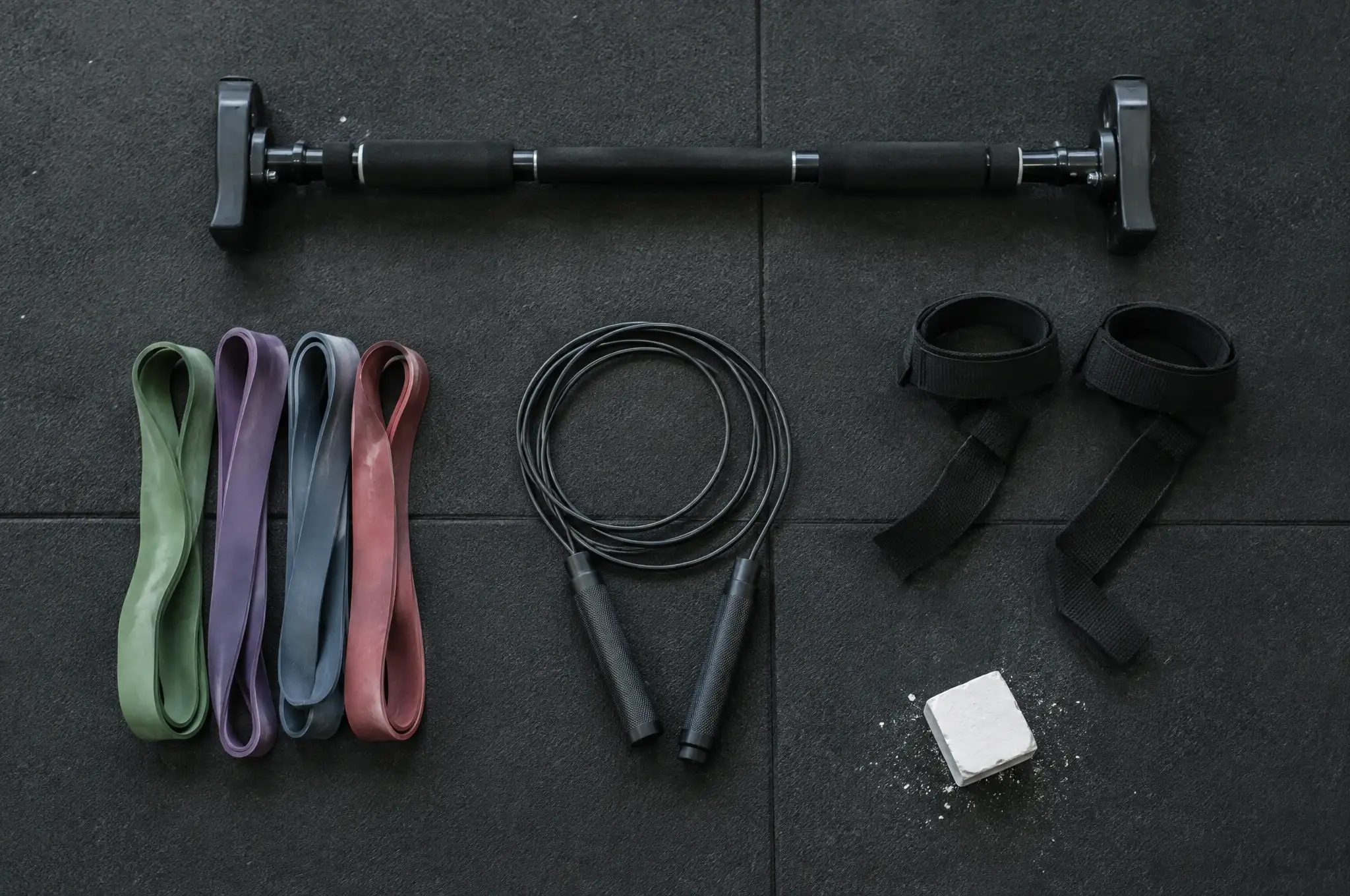Resistance bands, a doorway pull-up bar, a jump rope and chalk on a rubber floor