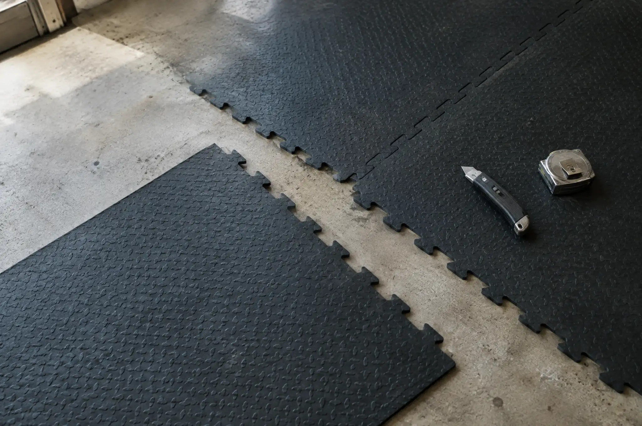Interlocking rubber gym tiles being laid on a concrete garage floor